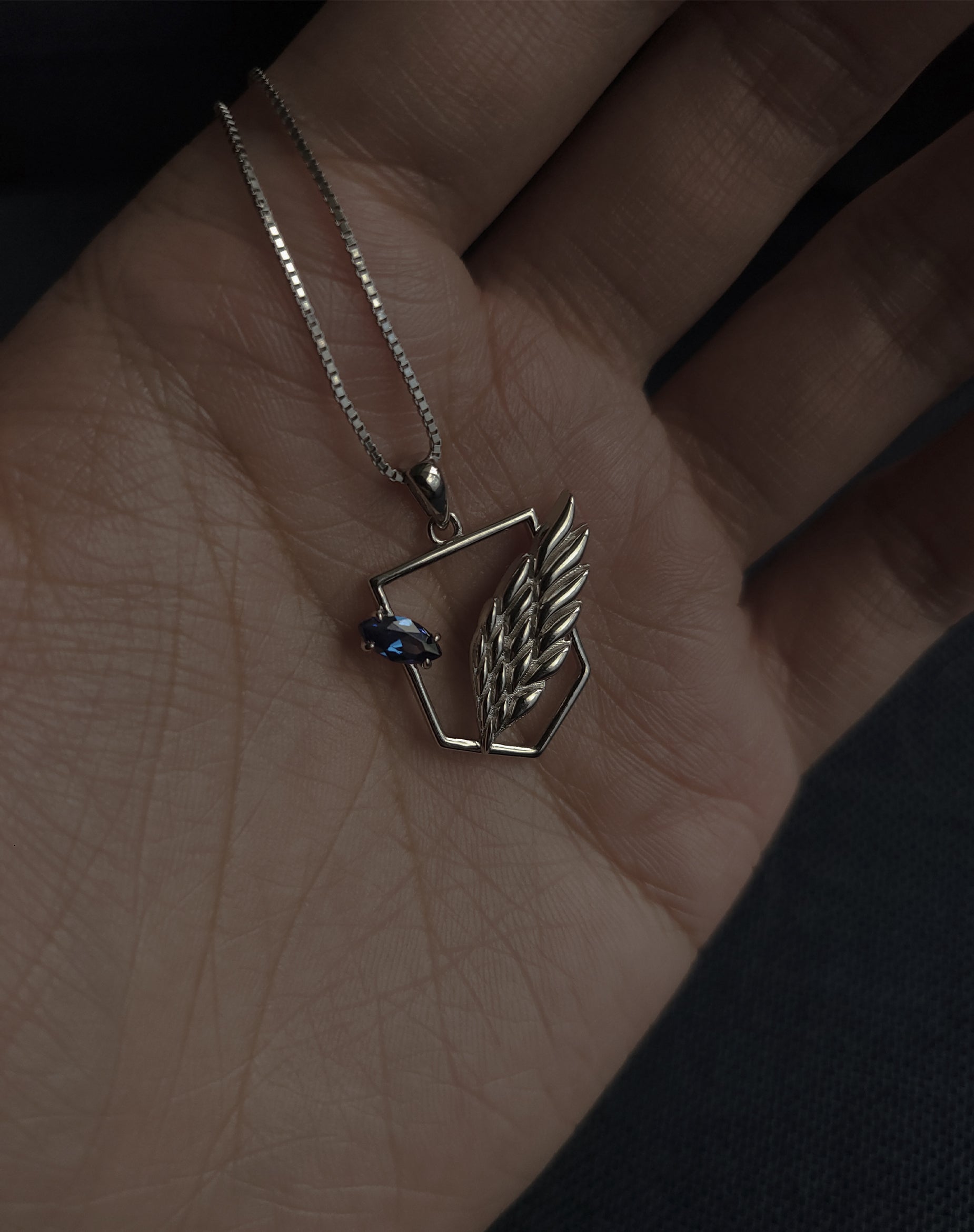 AOT Wings of freedom necklace close up in hand showing details