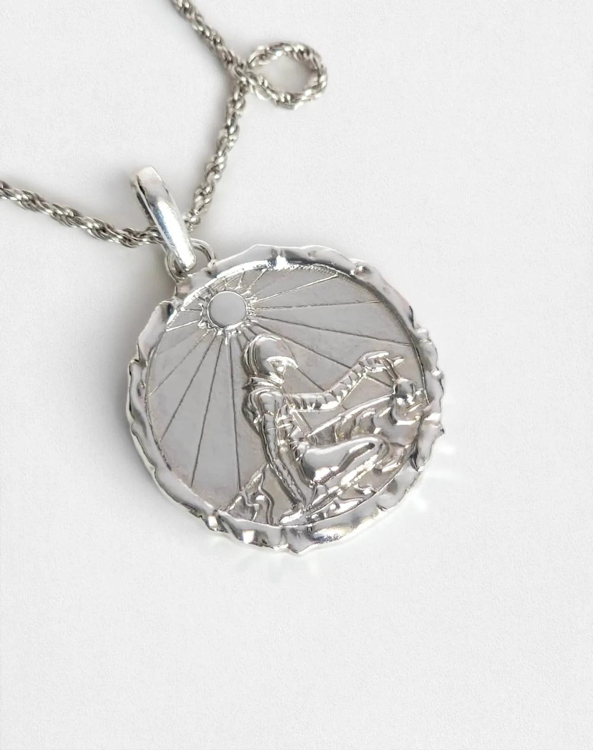 Close-up of silver Eclipse pendant necklace, showing figure detail.
